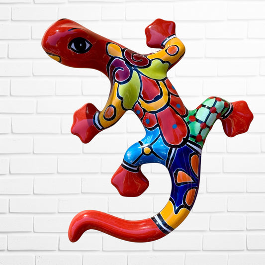 Colorful ceramic lizard sculpture against a white brick wall background