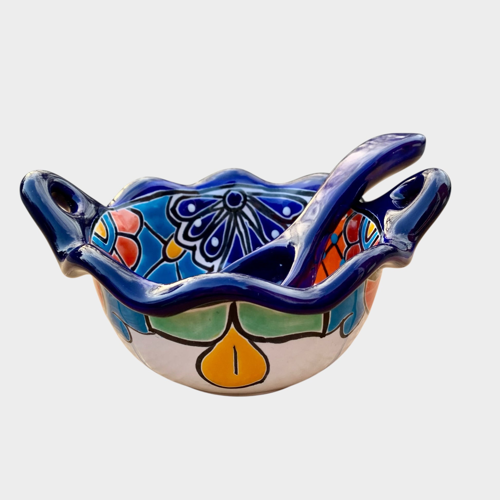 Colorful talavera salsa bowl with floral patterns and spoon on a white background Side view