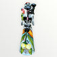 A Day of the Dead Catrina of a Frida skeleton doll holding a black cat, with a red parrot on her shoulder and colorful flowers around the top of her dress. Back view showing the back of her dress with a bow. 