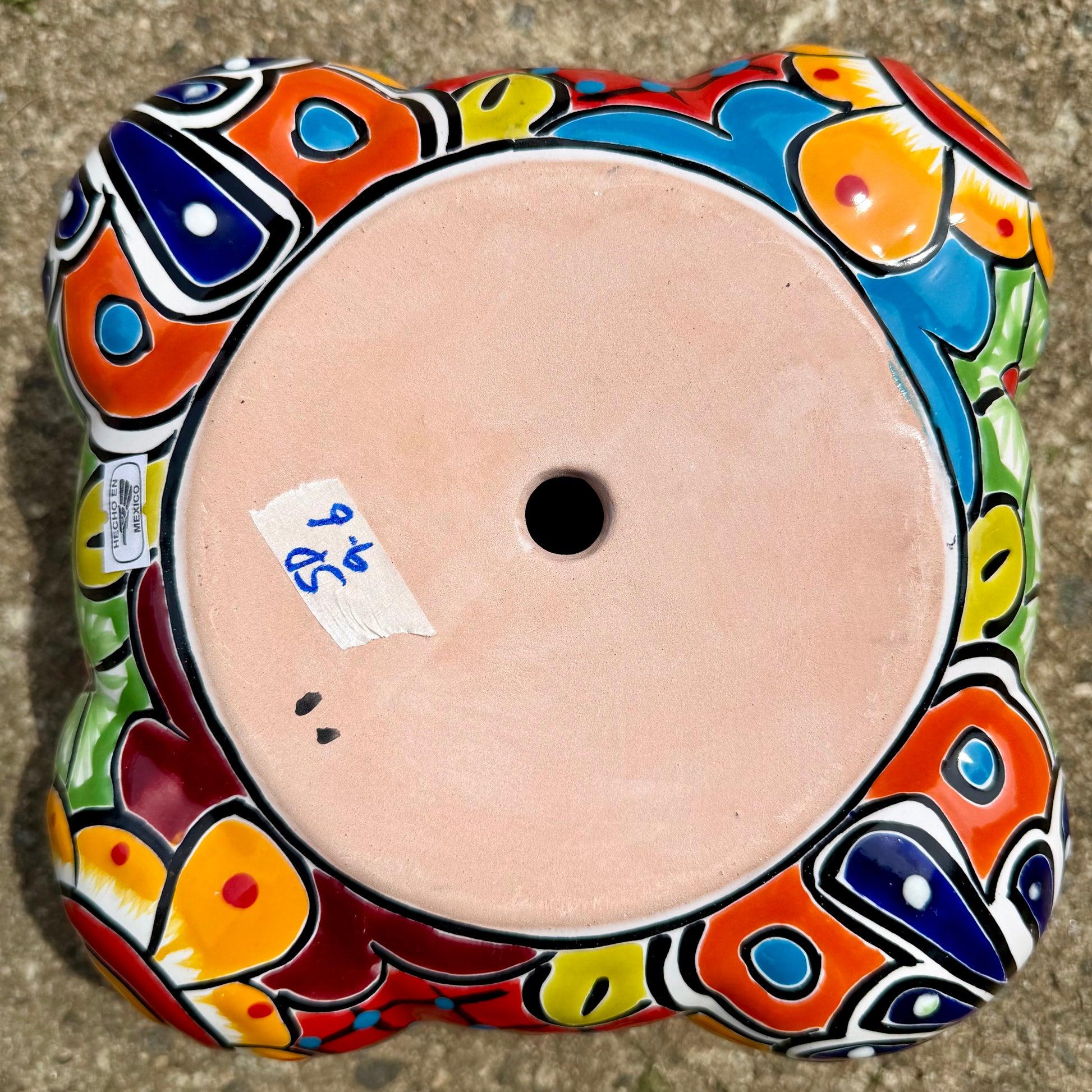Hand painted Mexican Talavera Strawberry pot with a large top opening a four pockets on each side.  Trim color is turquoise body has multi-color designs. Bottom view showing drain hole.