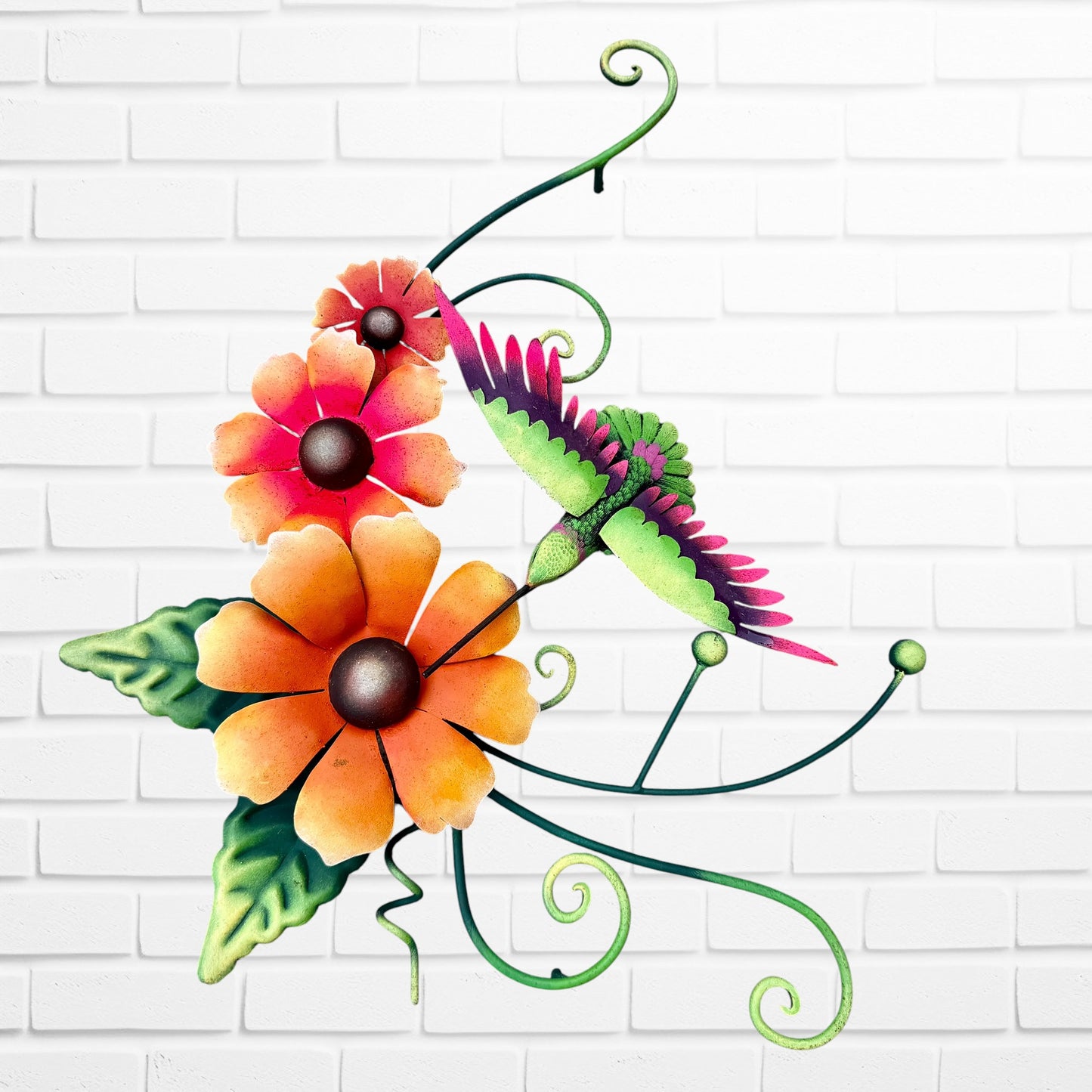 Decorative metal wall art with orange flowers and a hummingbird on a white brick background