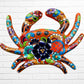 A colorful orange talavera crab wall art sculpture decorated with vibrant floral patterns, shown against a white brick wall background, top shell view.