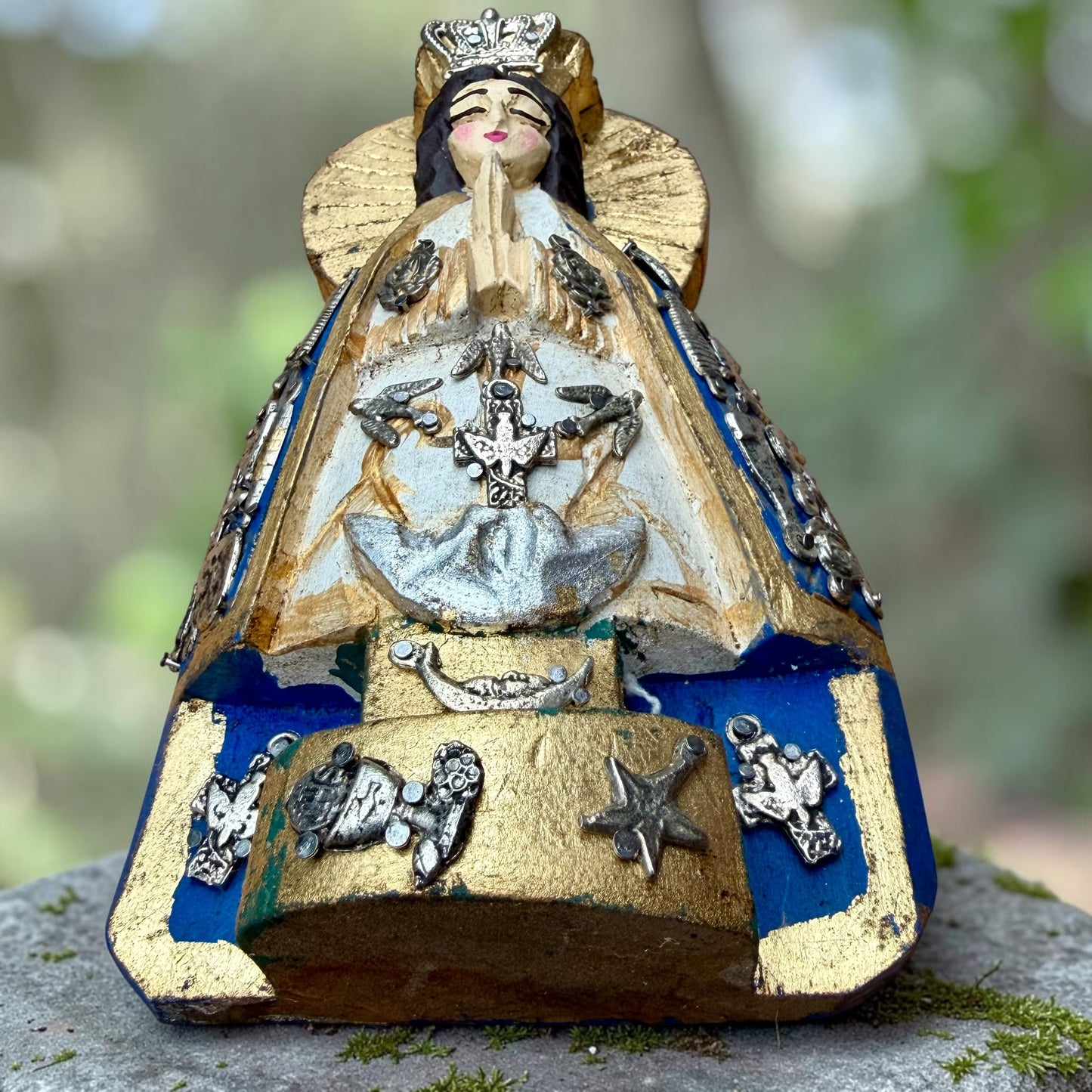 Angled view of Milagros Virgin Mary Salud showing her halo, crown and charms on her blue robe.