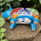 Colorful Talavera ceramic pig planter on a stone surface with green plants in  Background Bottom, drain hole