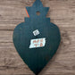 A Mexican Milagros large heart in black with a gold and red flaming top, covered in antiqued golden charms, back view,
