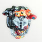 A Day of the Dead Catrina of a Frida skeleton doll holding a black cat, with a red parrot on her shoulder and colorful flowers around the top of her dress. Top view of Frida showing monkey, parrot and floral headband.