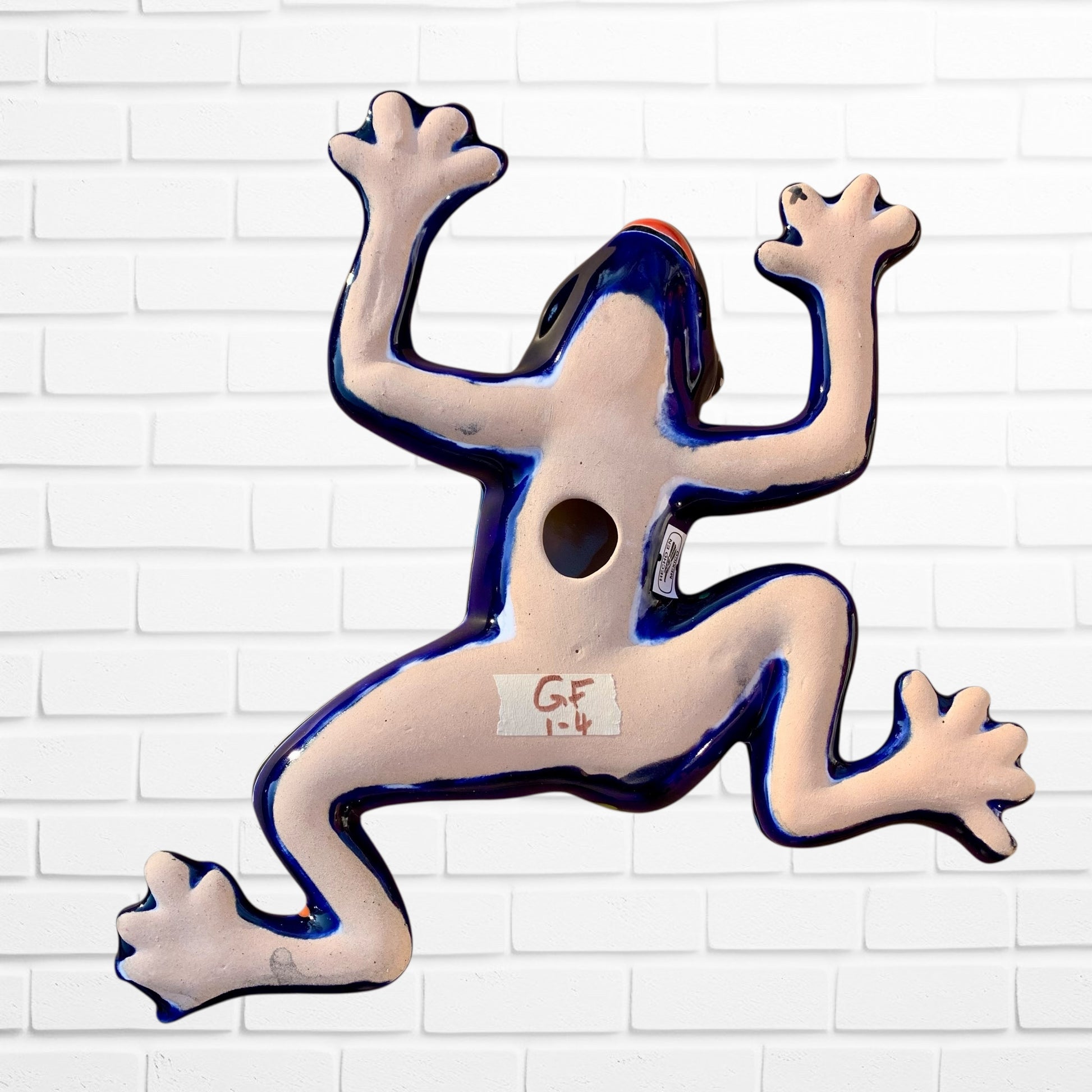 Decorative ceramic frog sculpture on a white brick wall background back