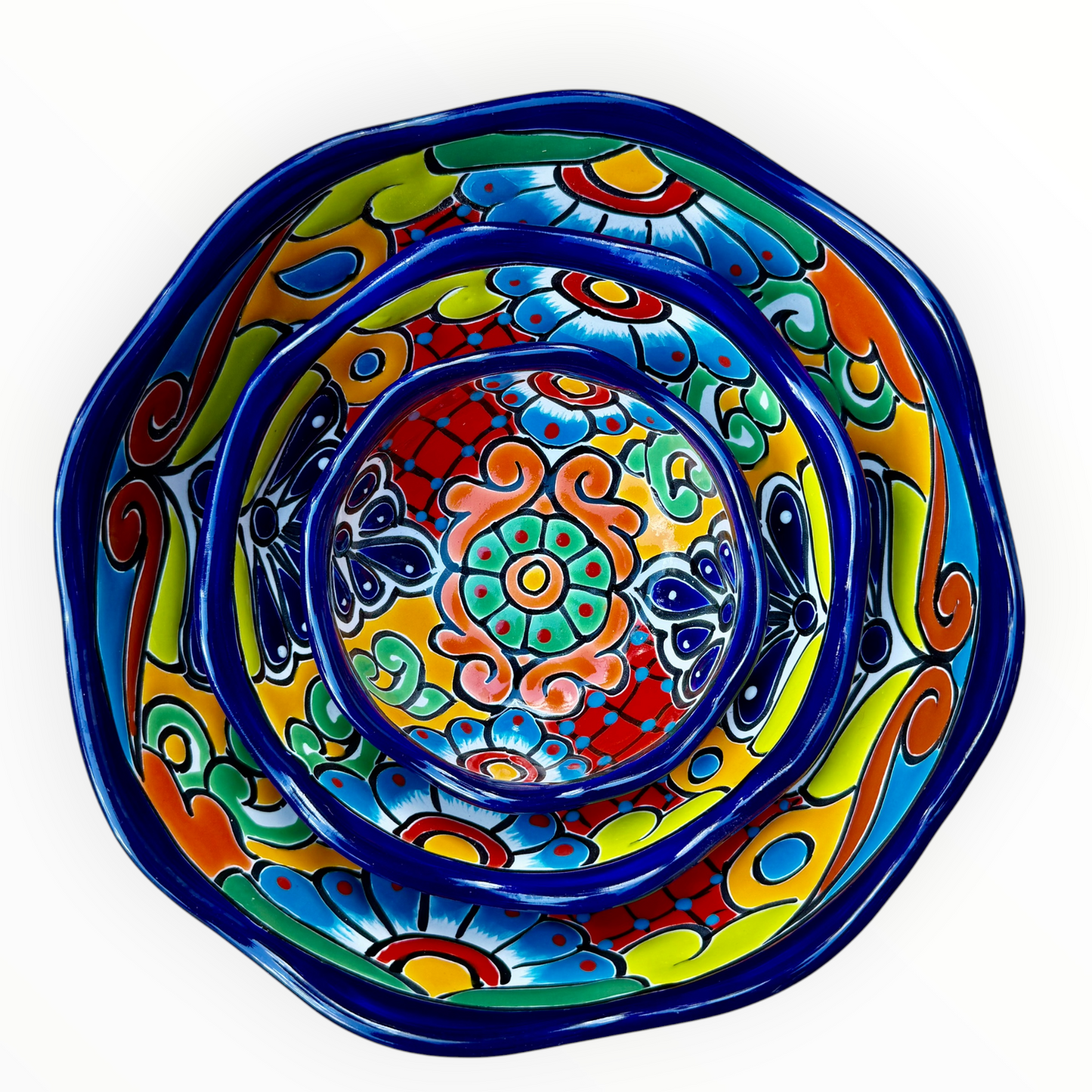 A set of three nested Talavera ceramic bowls with a vibrant hand-painted floral and geometric pattern in multiple colors, featuring a deep blue rim, shown on a plain white background.