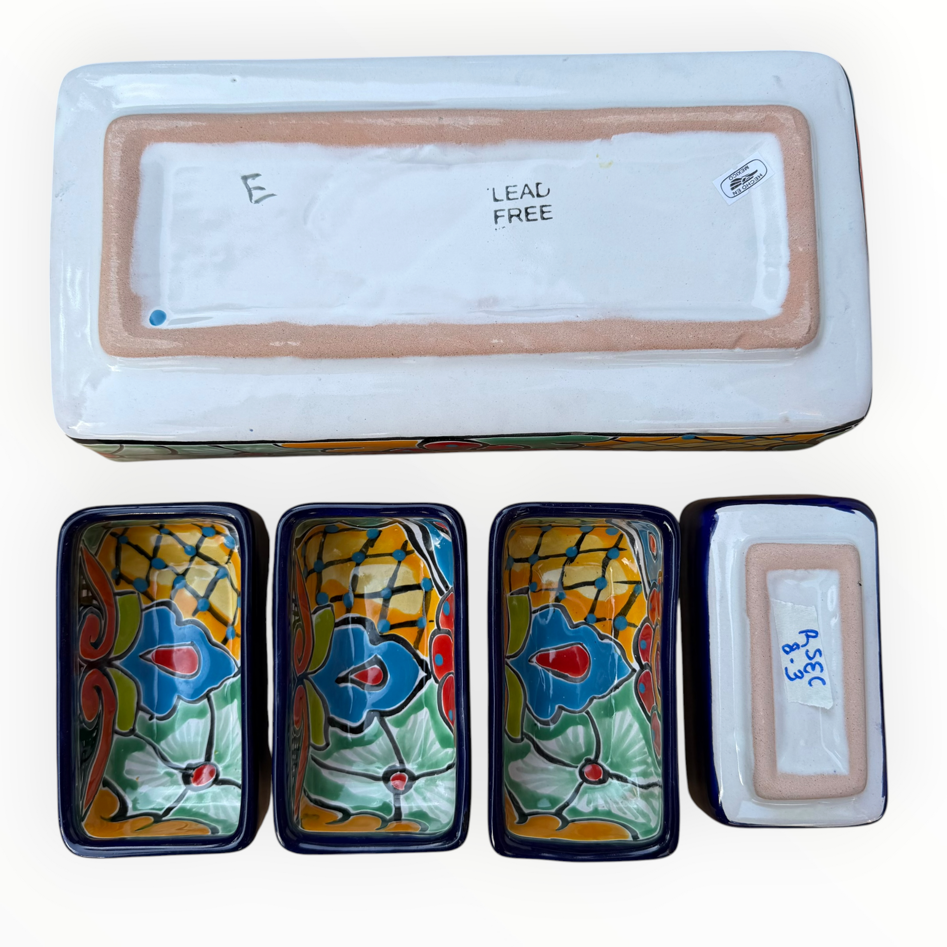A red ceramic four-compartment serving tray with hand-painted talavera designs in blue, orange, green, and yellow on a white background, bottom view.