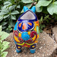 Colorful Talavera ceramic pig planter on a stone surface with green plants in  Background back view
