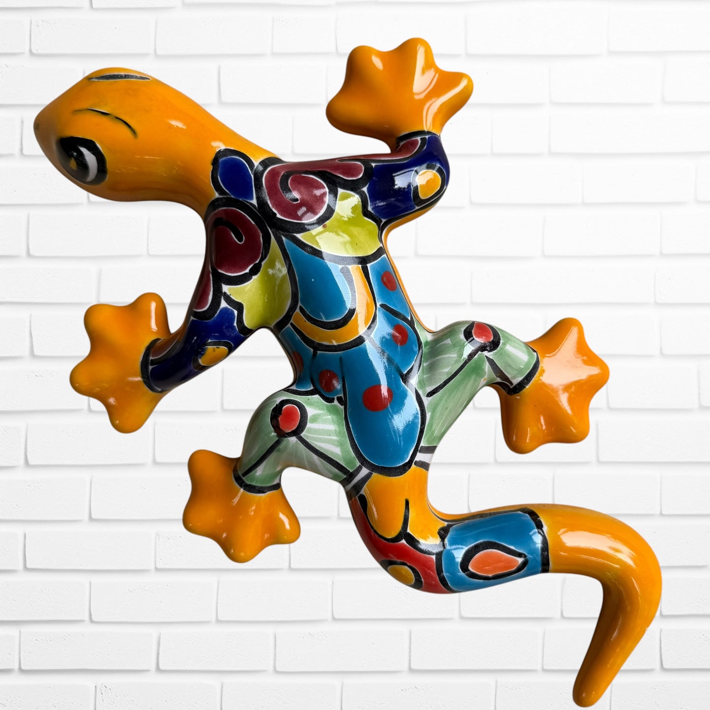 Second colorful hand-painted ceramic gecko wall sculptures in a vibrant Mexican folk art style, against a white brick wall.