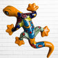 Second colorful hand-painted ceramic gecko wall sculptures in a vibrant Mexican folk art style, against a white brick wall.