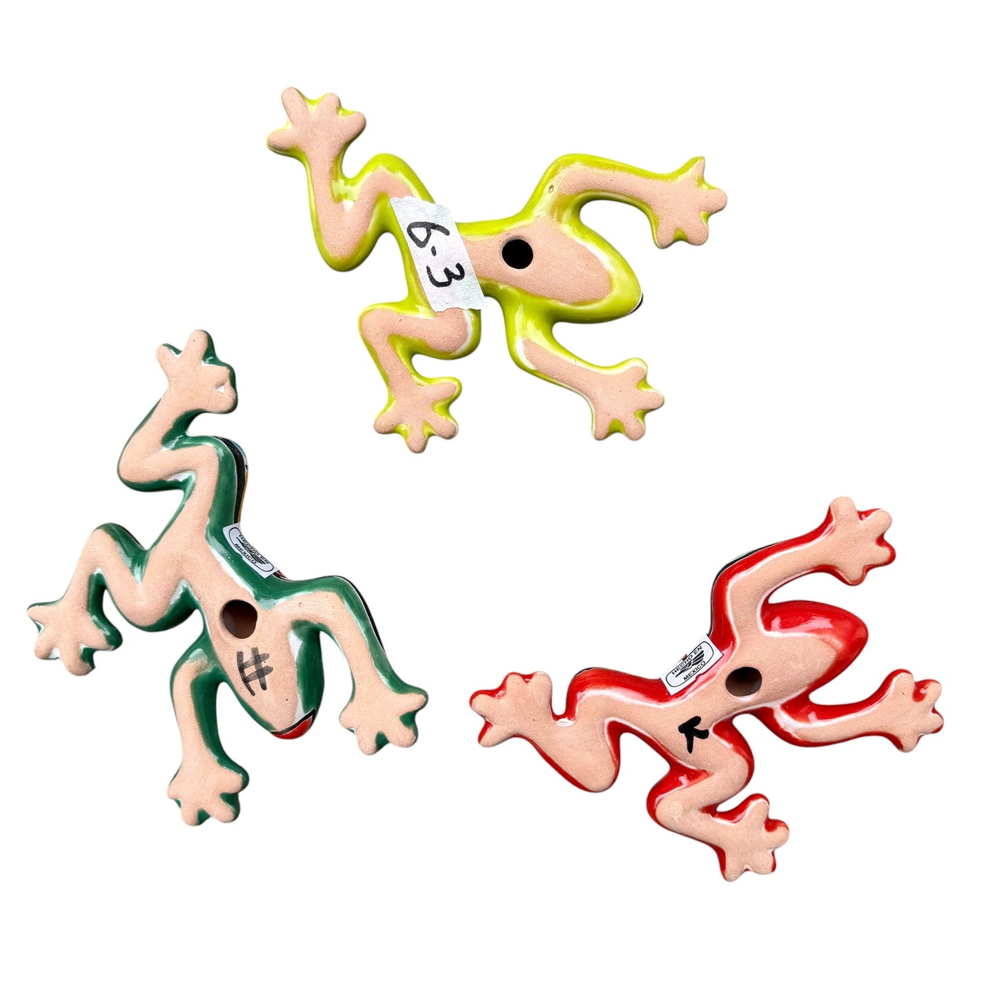 Three colorful ceramic frogs on a white background Back view
