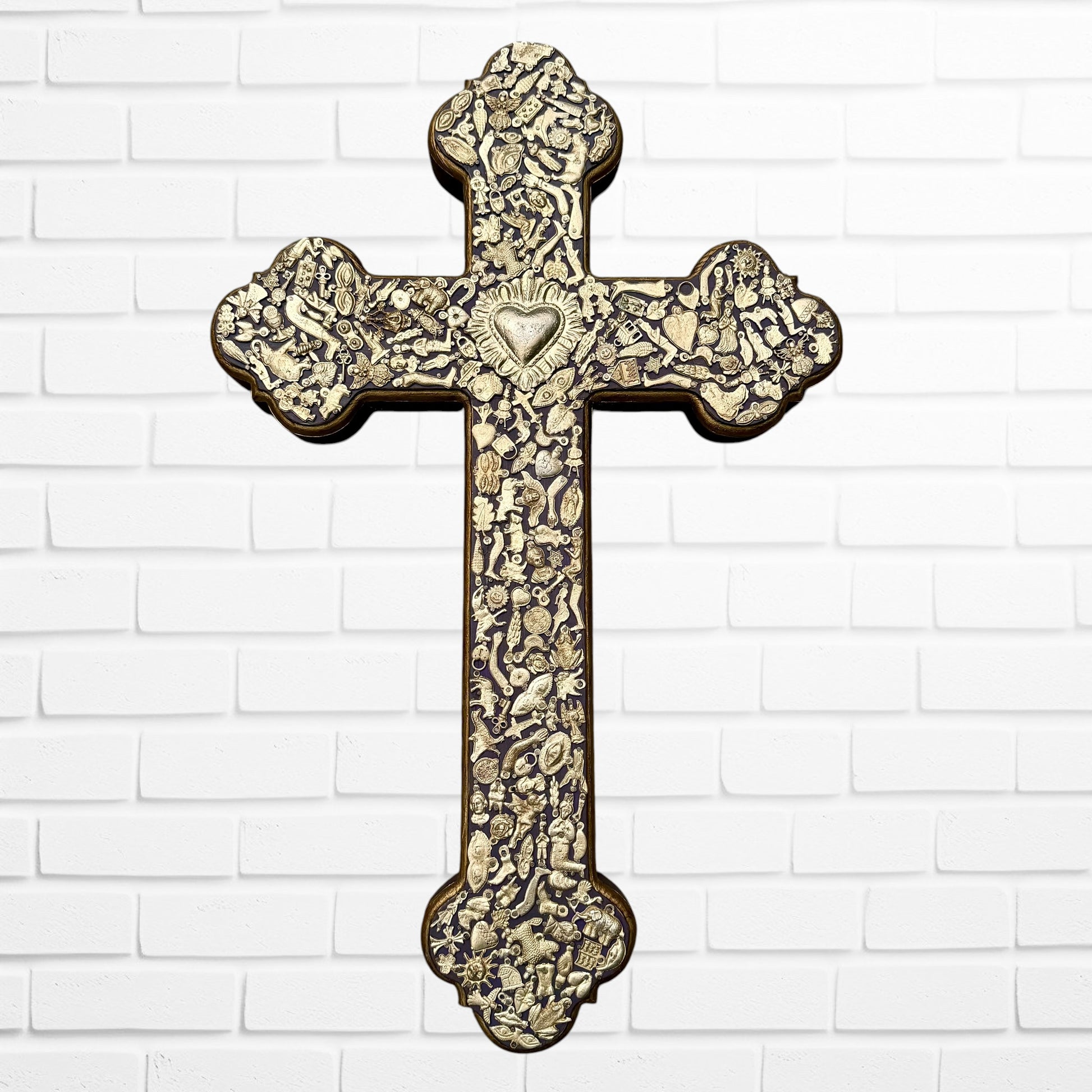 Decorative Milagros wood cross with many charms “miracles” on a white brick wall background