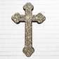 Decorative Milagros wood cross with many charms “miracles” on a white brick wall background