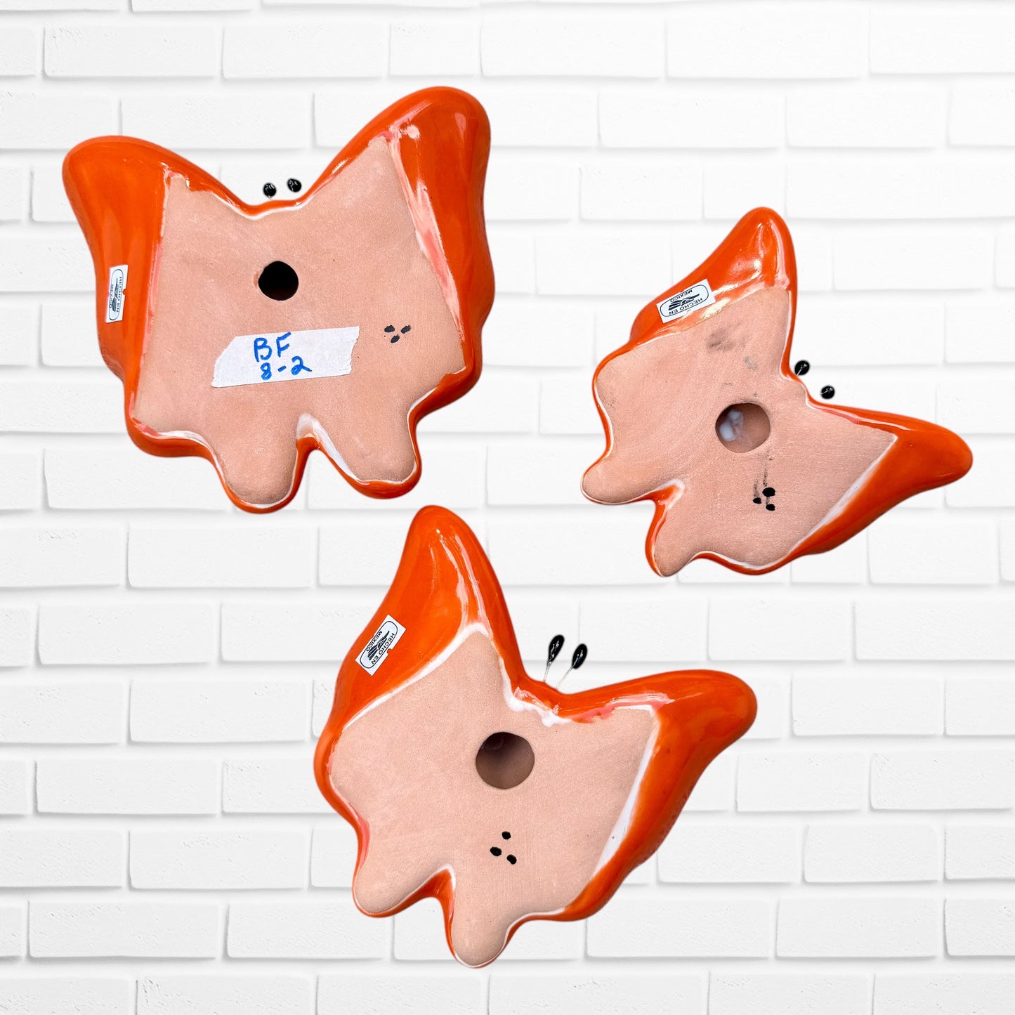 Three colorful talavera butterfly wall art pieces with orange and traditional multicolor patterns, back view.