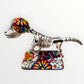 A ceramic Mexican-style skeleton dog figurine standing on a colorful floral base against a plain white background. Right side view of dog.