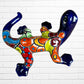 A colorful glazed ceramic lizard wall sculpture with a vibrant multicolor pattern, displayed against a white brick wall background back side leg View.