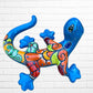 Colorful lizard-shaped wall art against a white brick wall background left side