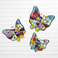 Three colorful ceramic Talavera butterfly wall art pieces with orange, blue, green, yellow, and purple mosaic patterns, displayed against a white brick wall.