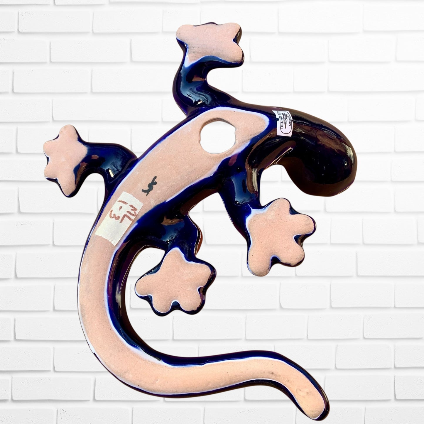 Decorative wall piece shaped like a lizard on a white brick wall background back