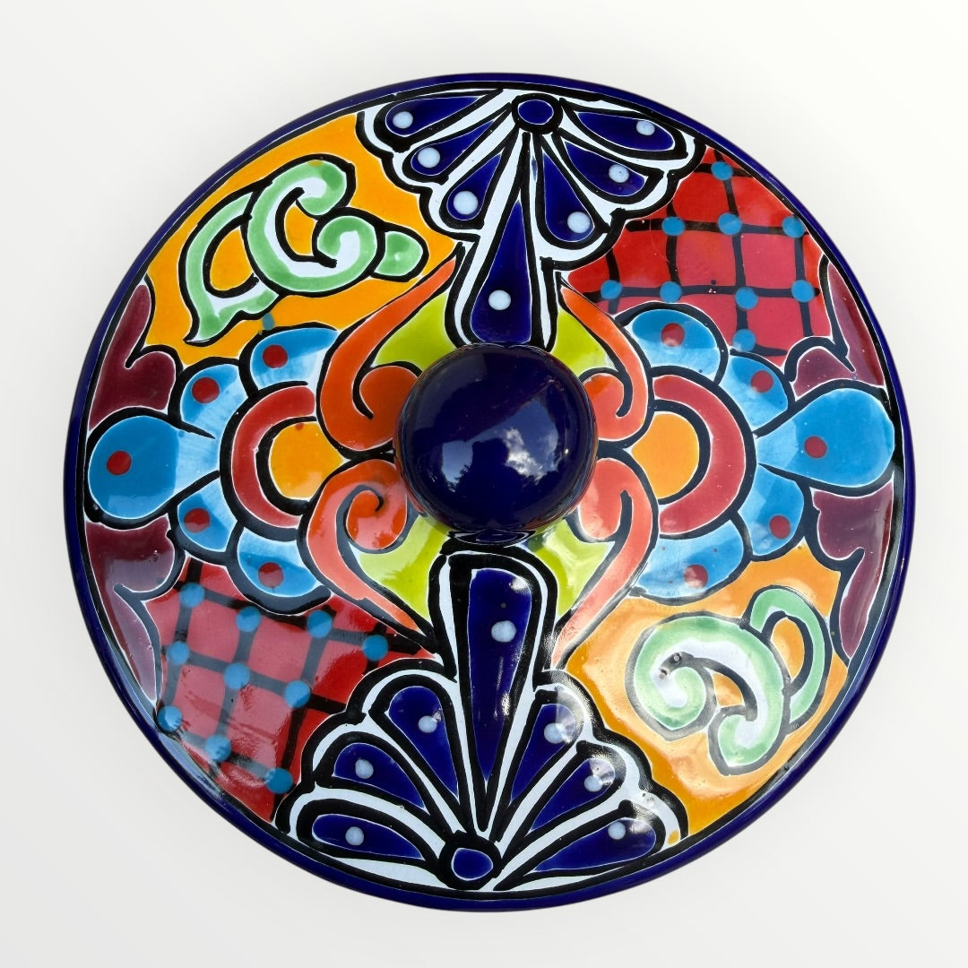 Mexican covered tortilla serving piece with blue rim and multi-color designs, top view with cover on.