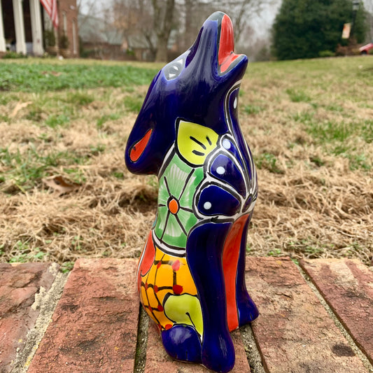 Colorful Talavera Coyote figurine on a brick surface with a grassy area in the background