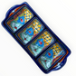 A red ceramic four-compartment serving tray with hand-painted talavera designs in blue, orange, green, and yellow on a white background, top view.