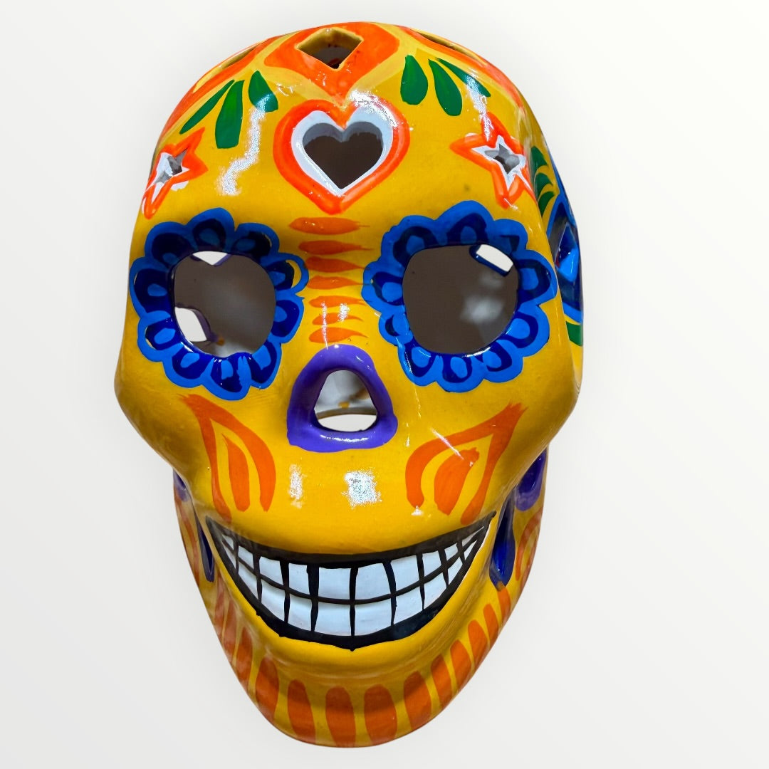 A hand-painted ceramic sugar skull in vibrant yellow, decorated with colorful floral and geometric patterns in blue, purple, green, orange, and red, set against a plain white background Front face view.