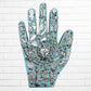 Decorative wall art of a hand with religious symbols on a white brick wall background blue