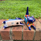 Two cobalt blue with multi-color designs hand-painted talavera ceramic cat figurines resting on a brick ledge with a green grassy lawn bottom figurine view.
