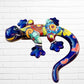 Colorful blue ceramic lizard sculpture on a white brick wall right side 