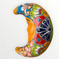 Decorative ceramic crescent moon with colorful patterns on a white background curved side