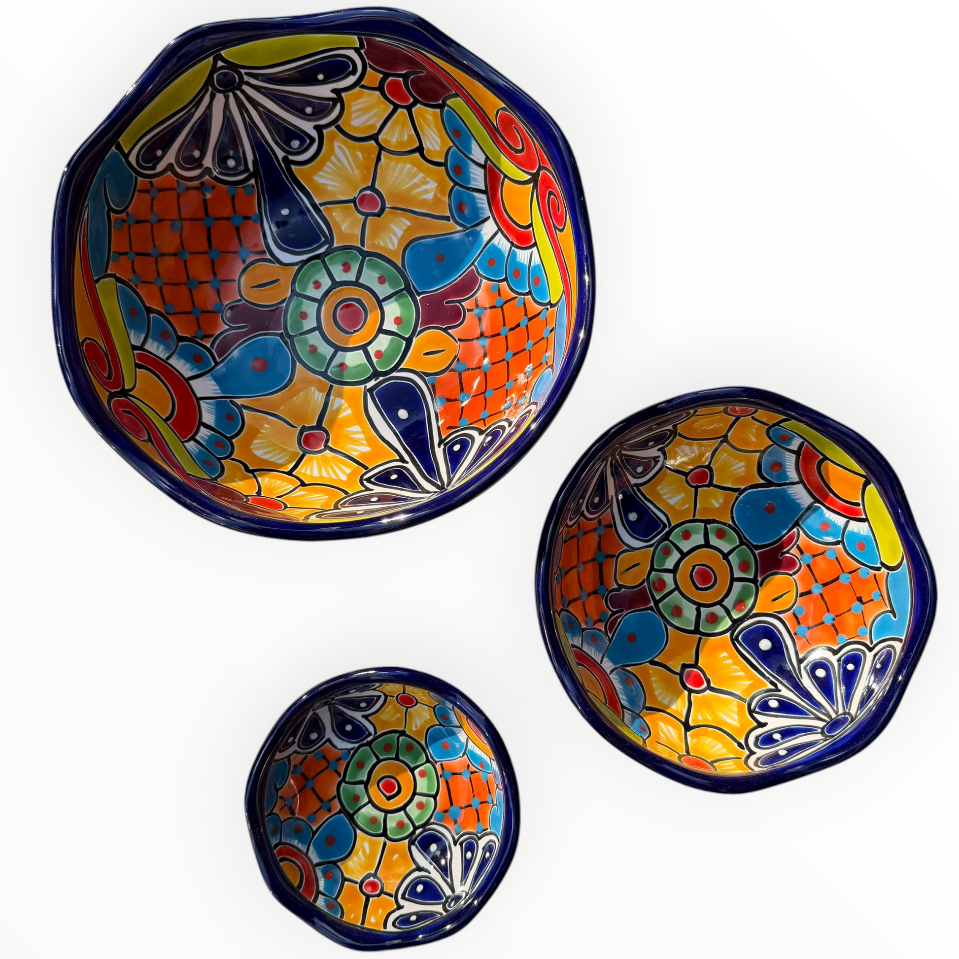 A set of nested, round Talavera ceramic bowls decorated with a vibrant, hand-painted Mexican Talavera style pattern featuring blue, yellow, orange, red, and green designs on a white background, View of all three bowls separated.