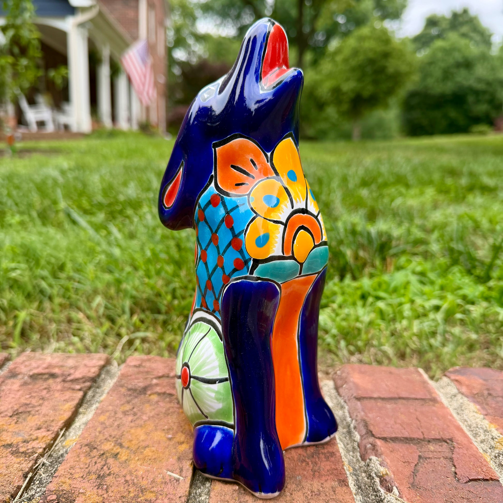 Coyote figurine on a brick surface with a garden background