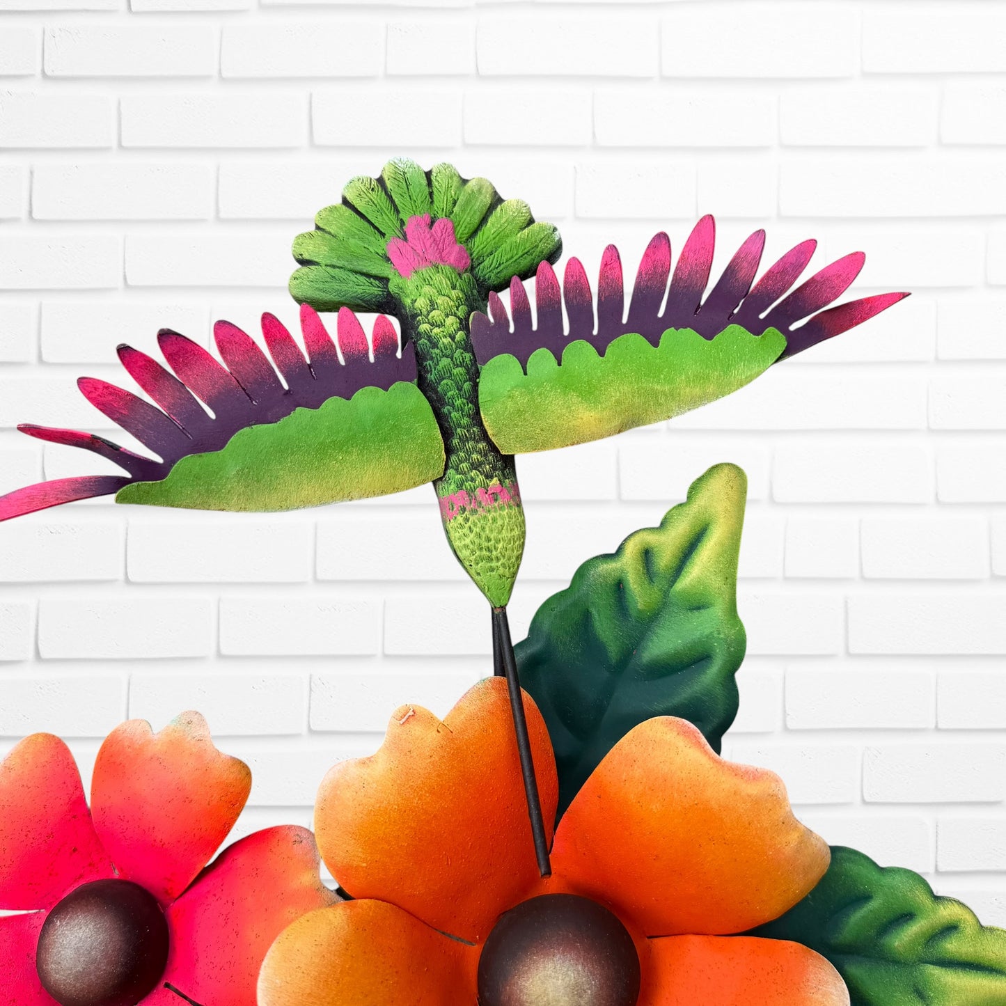 Decorative wall art with three orange flowers and hummingbird on a white brick wall background hummingbird close up