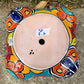 Hand painted Mexican Talavera Strawberry pot with a large top opening a four pockets on each side.  Trim color is bright happy yellow, body has multi-color designs on each of the four sides. Photo of bottom drain hole.