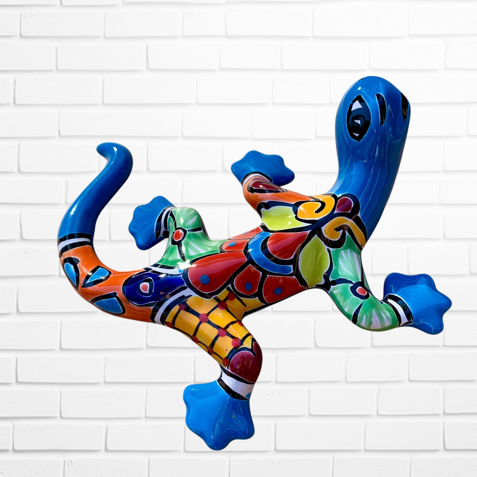 Colorful lizard-shaped inflatable pool toy against a white brick wall background left side