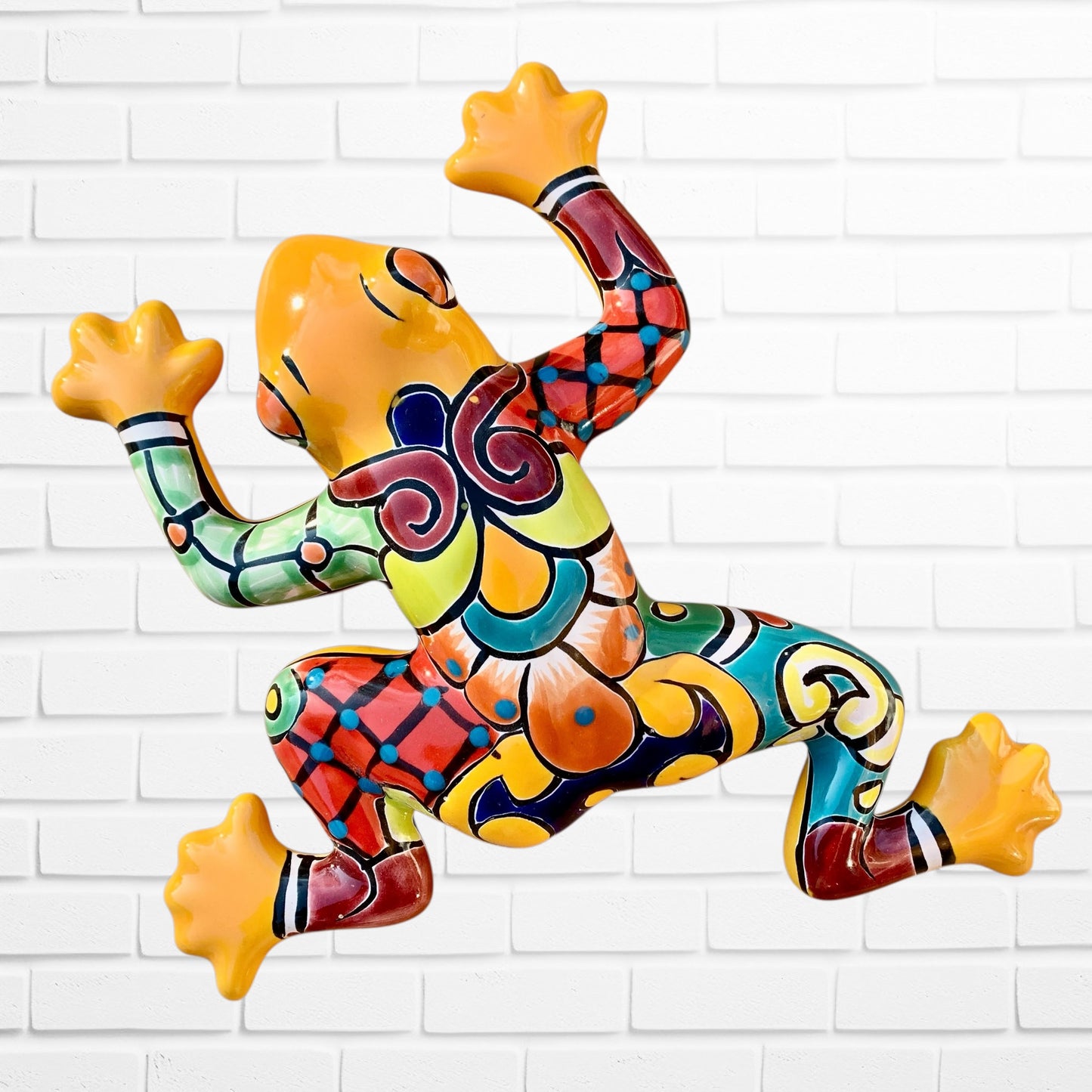 Colorful frog sculpture on a white brick wall