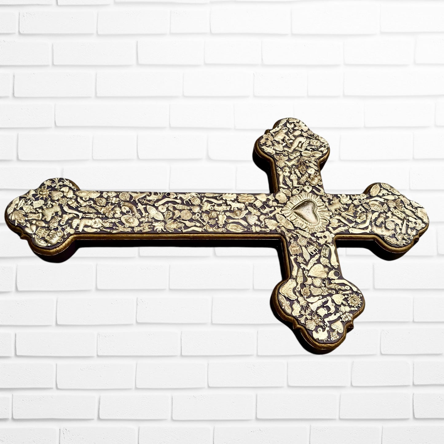 Decorative Milagros wood cross with many charms “miracles” on a white brick wall background Right side 