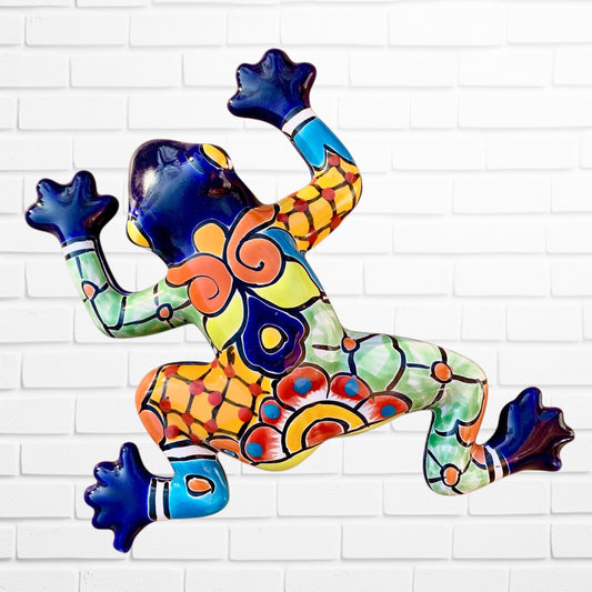 Colorful blue frog sculpture on a white brick wall
