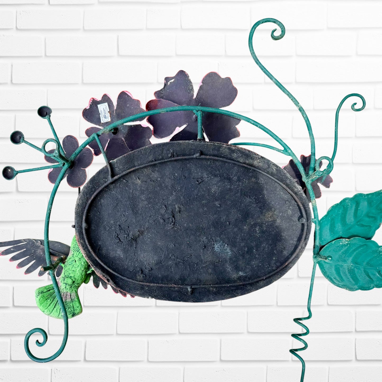 Decorative 'Welcome' sign with pink flowers and a hummingbird on a white brick wall background back view