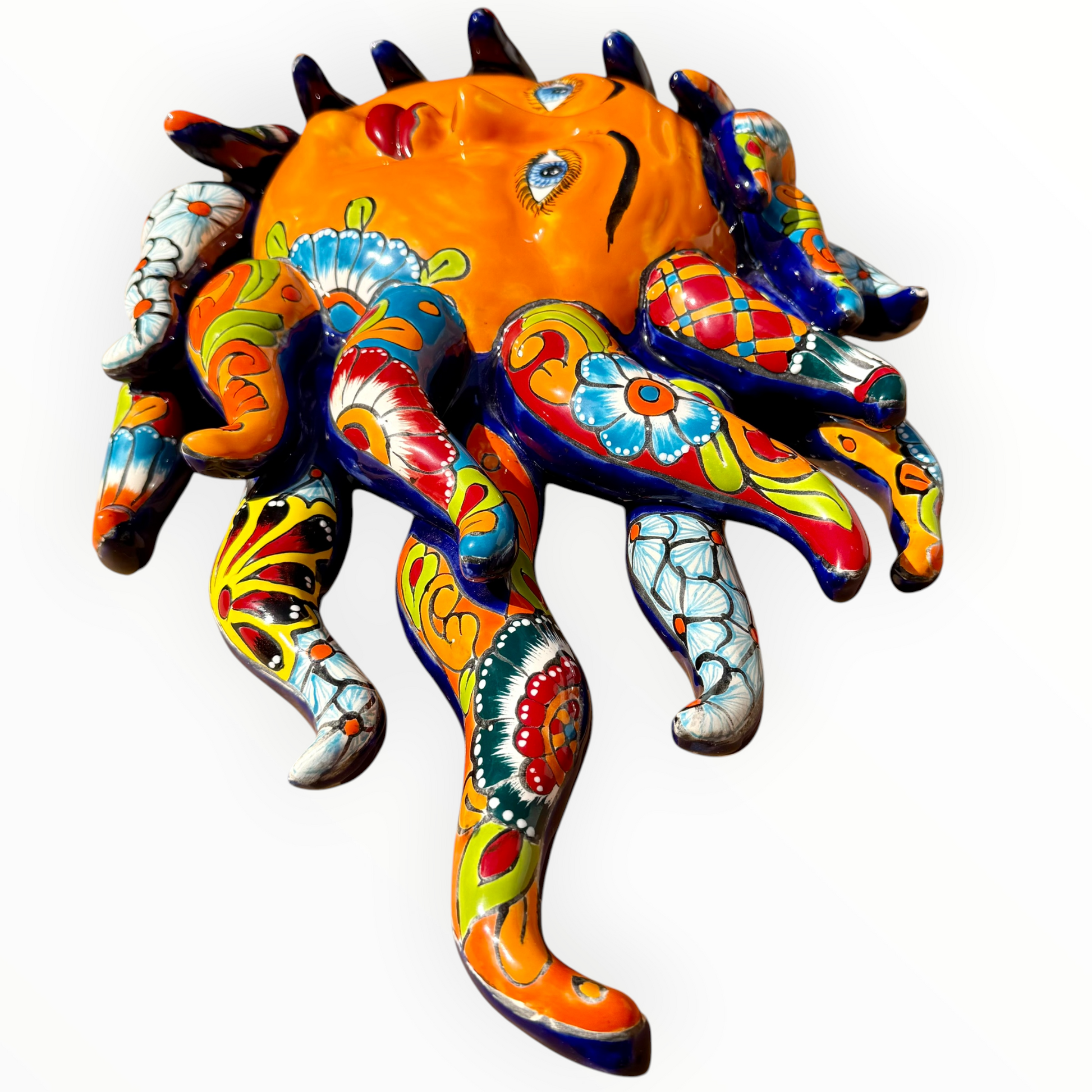 A colorful hand-painted Talavera ceramic sun wall sculpture with big wavy rays on a plain white background, Ray side view.