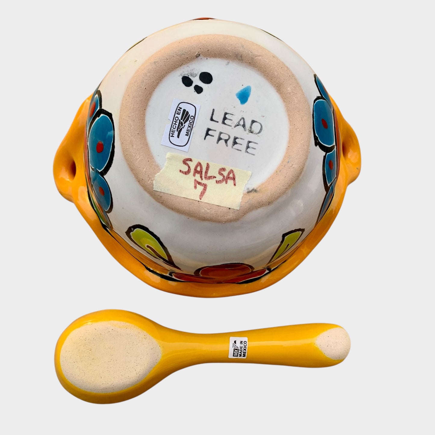 Colorful talavera salsa bowl with floral patterns and spoon on a white background Bottom view