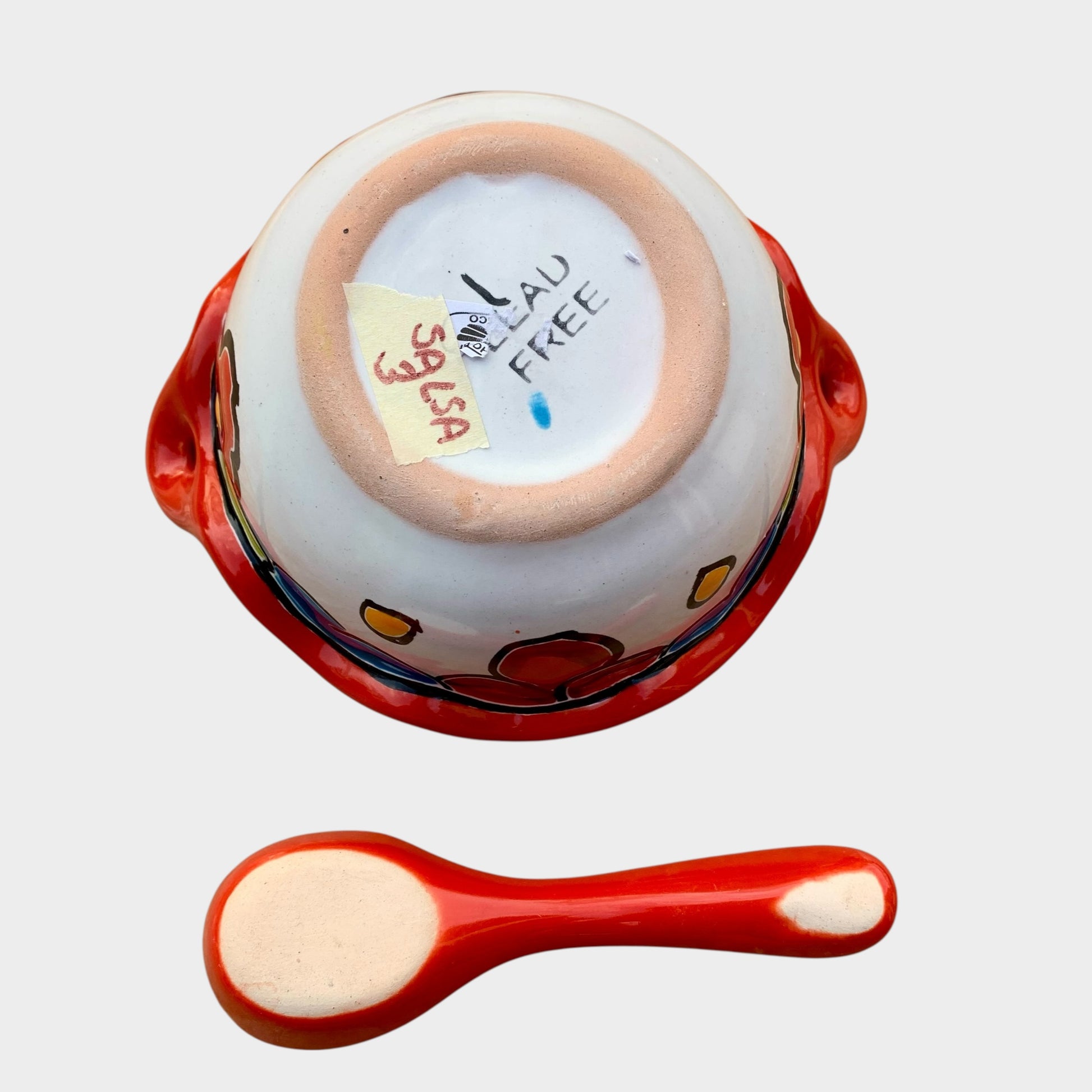 Colorful talavera salsa bowl with floral patterns and spoon on a white background Bottom view