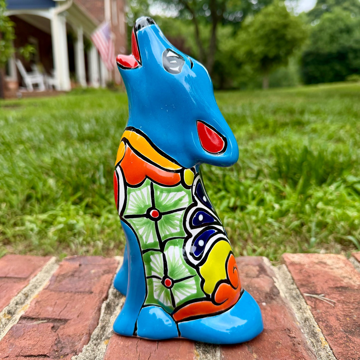 Coyote figurine on a brick surface with a garden background Right side view