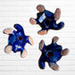 Three colorful hand-painted ceramic sea turtle wall art pieces displayed against a white painted brick wall, back view with holes to hang on wall.