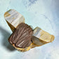 Milagros wooden guardian angel figurine wearing a yellow robe with gold and silver metallic details, standing on a light blue textured background, top view.