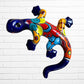 A colorful ceramic wall sculpture of a stylized lizard or salamander, decorated with vibrant hand-painted patterns in blue, red, yellow, and orange, mounted on a white brick wall.