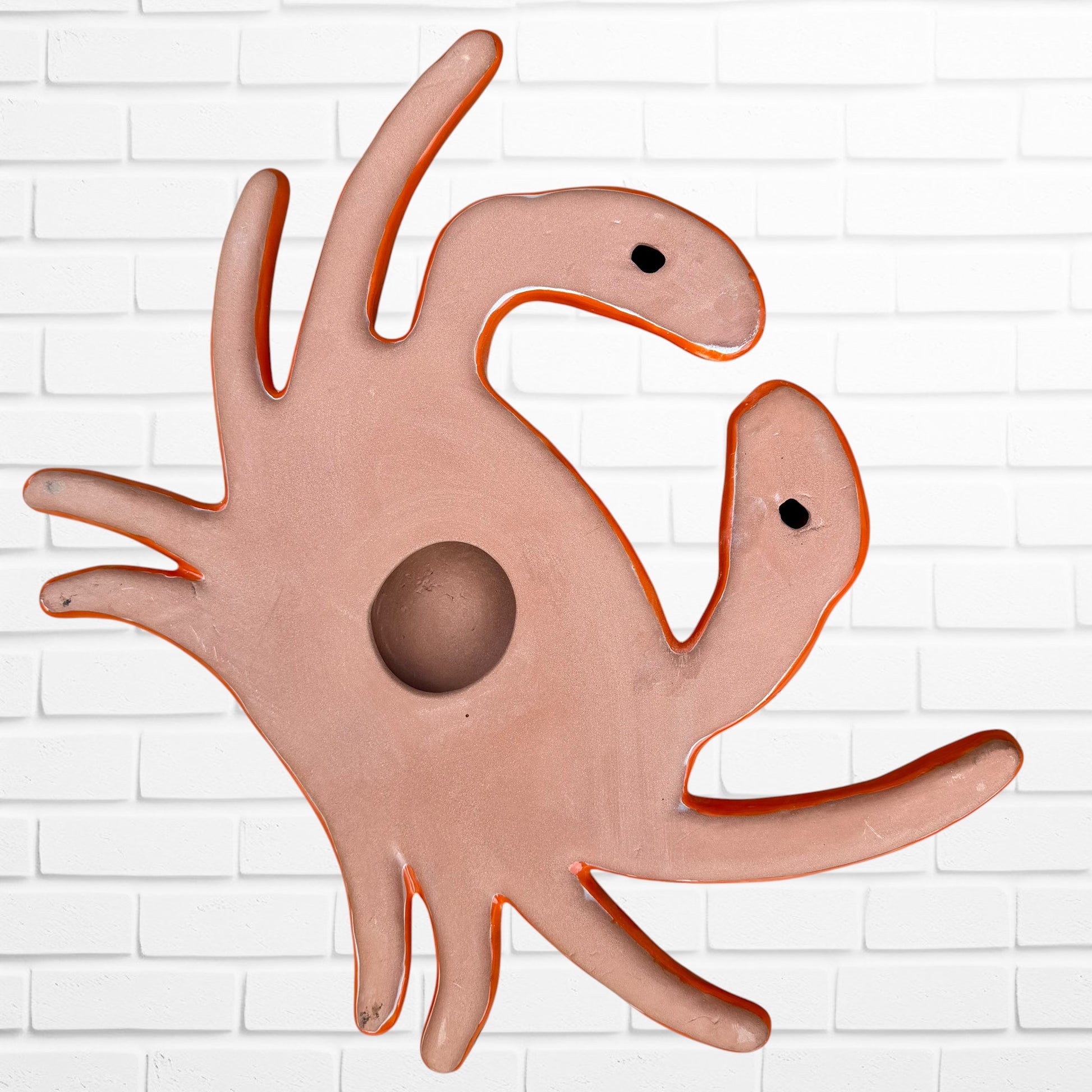 A colorful talavera crab wall art sculpture decorated with vibrant floral patterns, shown against a white brick wall background, back view with hanging hole.